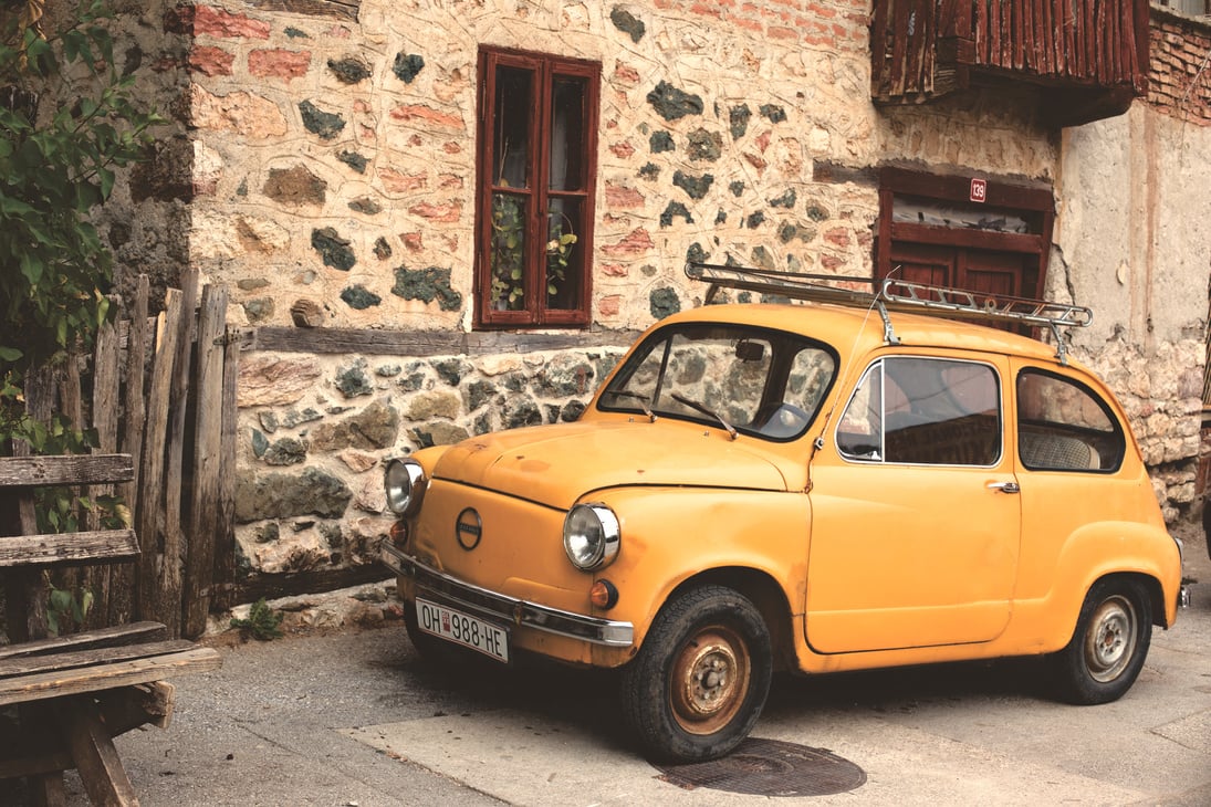 Yellow Nissan Classic Car Beside Gray Beige Concrete Building